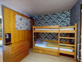 This charming room features a space-saving bunk bed, perfect for families or groups, complemented by a stylish tropical-themed wallpaper.
