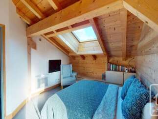 Experience cozy living in this charming attic bedroom, featuring exposed wooden beams and a skylight that floods the space with natural light.