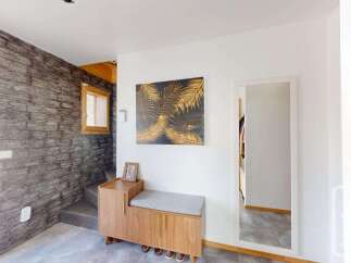 Step into this inviting entryway featuring a striking stone accent wall and a stylish wooden bench with storage.