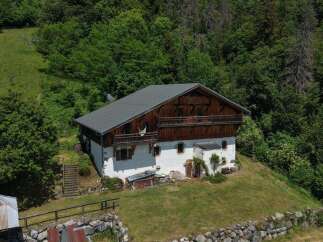 Nestled amidst lush greenery, this charming alpine chalet offers a serene retreat with its traditional wooden architecture and white-washed walls.