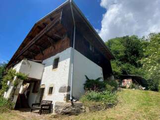 Discover this charming rustic property nestled amidst lush greenery, featuring a traditional wooden-clad upper level with a spacious balcony and a whitewashed lower section.