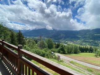 Experience breathtaking mountain views from this stunning property, featuring a charming wooden balcony perfect for enjoying the serene landscape.