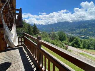Experience breathtaking mountain views from this charming wooden balcony, complete with a relaxing hammock.
