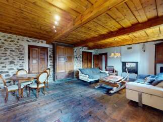 Experience rustic charm in this inviting living space, featuring exposed stone walls and a warm wooden ceiling.