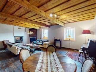Experience rustic charm in this inviting living space, featuring exposed wooden beams and a cozy fireplace.