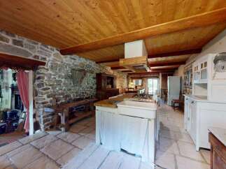 Experience rustic charm in this spacious kitchen featuring exposed stone walls and a warm wooden ceiling.