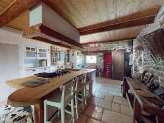 Experience rustic charm in this unique kitchen featuring exposed wooden beams and a stone wall.