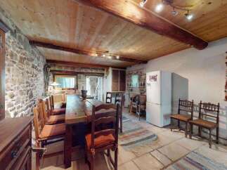 Experience rustic charm in this spacious dining area featuring a large wooden table perfect for gatherings.