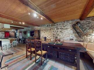 Experience rustic charm in this spacious kitchen featuring exposed stone walls and a warm wooden ceiling.