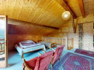 Experience rustic charm in this cozy wooden cabin bedroom, featuring two comfortable beds and a private balcony with stunning mountain views.