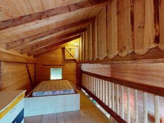 Experience rustic charm in this cozy wooden loft bedroom, featuring a comfortable bed and a charming railing overlooking the space.