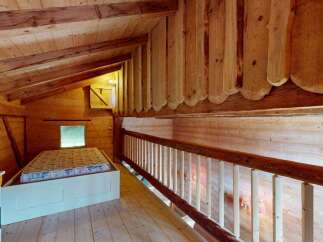 Discover this charming wooden loft featuring a cozy sleeping area with a mattress on a raised platform.