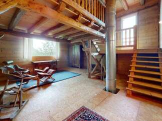Experience rustic charm in this cozy wooden cabin featuring a loft space accessible by a wooden staircase.