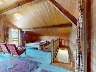 Experience rustic charm in this attic bedroom, featuring exposed wooden beams and a cozy ambiance.
