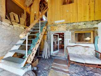 Discover rustic charm in this unique property featuring a charming staircase adorned with festive greenery, leading to an inviting interior.