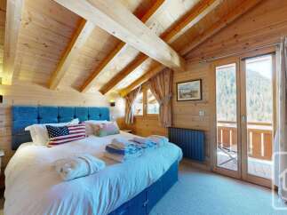 Experience rustic charm in this beautifully appointed bedroom, featuring a cozy king-sized bed with a striking blue headboard and a patriotic American flag accent pillow.