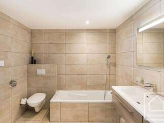 This modern bathroom features a sleek design with large beige tiles covering the walls and floor.