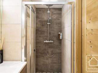 Experience modern comfort in this beautifully appointed bathroom, featuring a sleek glass-enclosed shower with a rainfall showerhead and convenient shelving for toiletries.