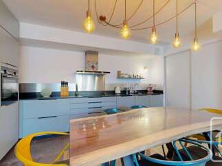 This modern kitchen boasts sleek, light blue cabinetry and a striking live-edge dining table, perfect for family meals.