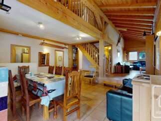 Experience rustic charm in this spacious log cabin featuring a large dining area with a wooden table and chairs, perfect for family gatherings.
