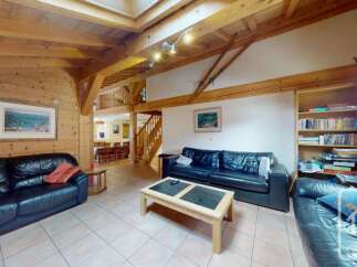 Experience rustic charm in this spacious living area, featuring exposed wooden beams and a cozy fireplace.