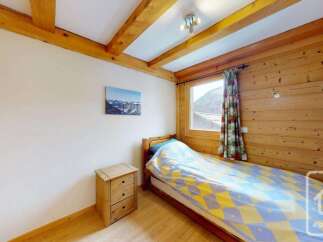 This charming bedroom features a cozy single bed with a vibrant yellow and blue patterned duvet, perfect for a restful night's sleep.