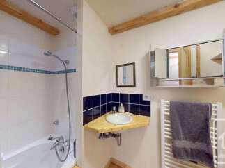 This charming bathroom features a bathtub with a shower, perfect for relaxing after a long day.