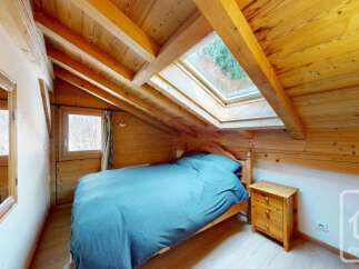 Experience cozy mountain living in this charming attic bedroom, featuring exposed wooden beams and a skylight that floods the space with natural light.