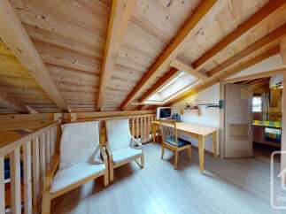 Discover this charming attic room featuring a cozy seating area with two comfortable chairs and a wooden desk perfect for a home office.
