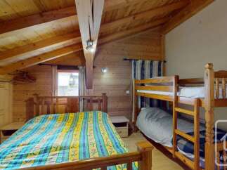 This charming alpine bedroom features a cozy double bed with a vibrant, patterned comforter, perfect for unwinding after a day of skiing.
