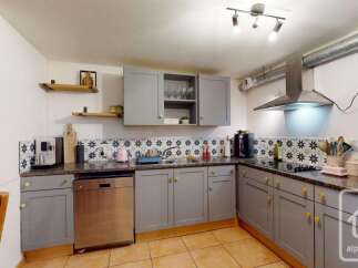 Discover this charming kitchen featuring sleek grey cabinetry and a modern stainless steel range hood.