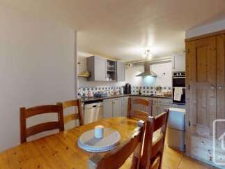 This charming kitchen and dining area features a rustic wooden dining table with chairs, perfect for family meals.