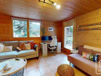 Experience cozy living in this charming wooden cabin, featuring a comfortable living area with a sectional sofa and a rustic coffee table.