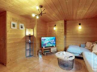 Experience cozy living in this charming wooden cabin, featuring a warm and inviting living area with a modern entertainment setup.