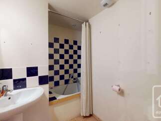 This bathroom features a classic checkerboard tile design around the bathtub and a convenient sink with soap dispenser.