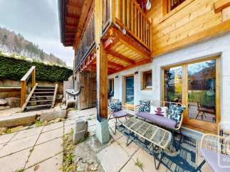 Enjoy the stunning mountain views from this charming chalet's outdoor patio, complete with comfortable seating and a rustic coffee table.