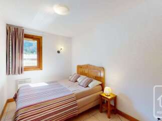 This cozy bedroom features a comfortable double bed with striped bedding, perfect for a restful night's sleep.