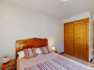 This charming bedroom features a comfortable wooden bed with striped bedding and decorative pillows, creating a cozy atmosphere.