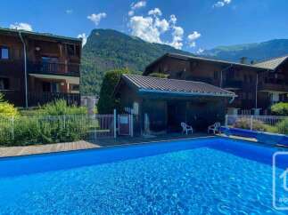 Enjoy a refreshing dip in the sparkling blue swimming pool, surrounded by lush greenery and the majestic backdrop of the Alps.