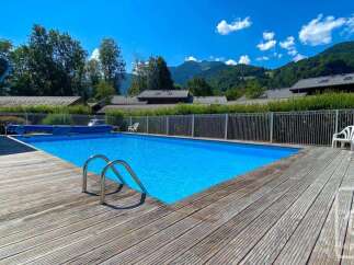 Enjoy a refreshing dip in the crystal-clear blue swimming pool, surrounded by a spacious wooden deck perfect for sunbathing.