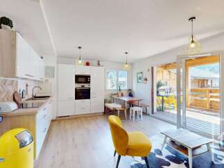 Discover this modern open-plan living space, featuring a sleek white kitchen with integrated appliances and ample counter space.