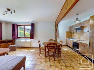 This charming living and dining area features a cozy round wooden table with four chairs, perfect for intimate meals.