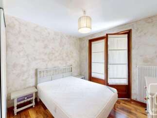 This charming bedroom features a comfortable bed with a white headboard, complemented by a light-colored textured wallpaper.