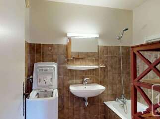 This bathroom features a top-loading washing machine, a white sink with a chrome faucet, and a bathtub with a showerhead.