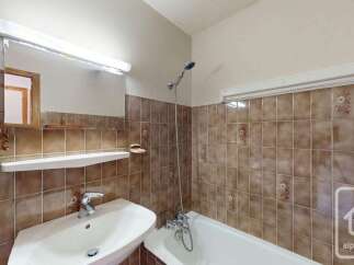 This bathroom features a classic tiled design with warm brown tiles and subtle floral accents.