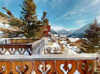Experience the charm of alpine living with this stunning property, featuring a beautifully crafted wooden balcony overlooking a picturesque snow-covered village.