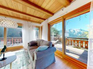Experience breathtaking mountain views from this stunning living room, featuring a cozy sofa and a unique, modern chandelier.