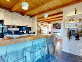 Experience modern alpine living in this stunning kitchen featuring a sleek black backsplash, ample white cabinetry, and a beautiful wooden countertop breakfast bar.