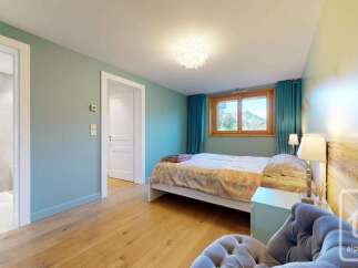 Experience breathtaking mountain views from this serene bedroom, featuring a comfortable queen-size bed and a cozy armchair.