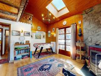 Experience rustic charm in this mountain retreat, featuring a cozy living area with a foosball table and a wood-burning stove.